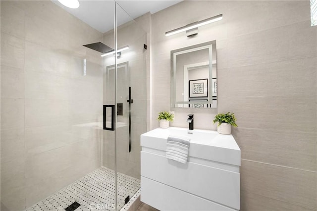 full bath featuring a stall shower, vanity, and tile walls