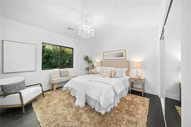 bedroom with a chandelier, dark wood-type flooring, visible vents, and baseboards