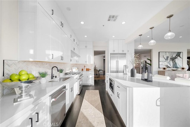 kitchen with visible vents, built in appliances, a sink, light countertops, and backsplash