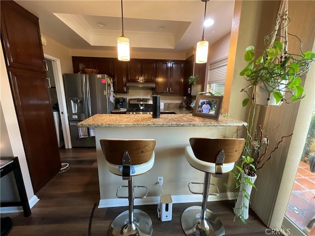 kitchen featuring dark hardwood / wood-style flooring, kitchen peninsula, a breakfast bar area, and appliances with stainless steel finishes