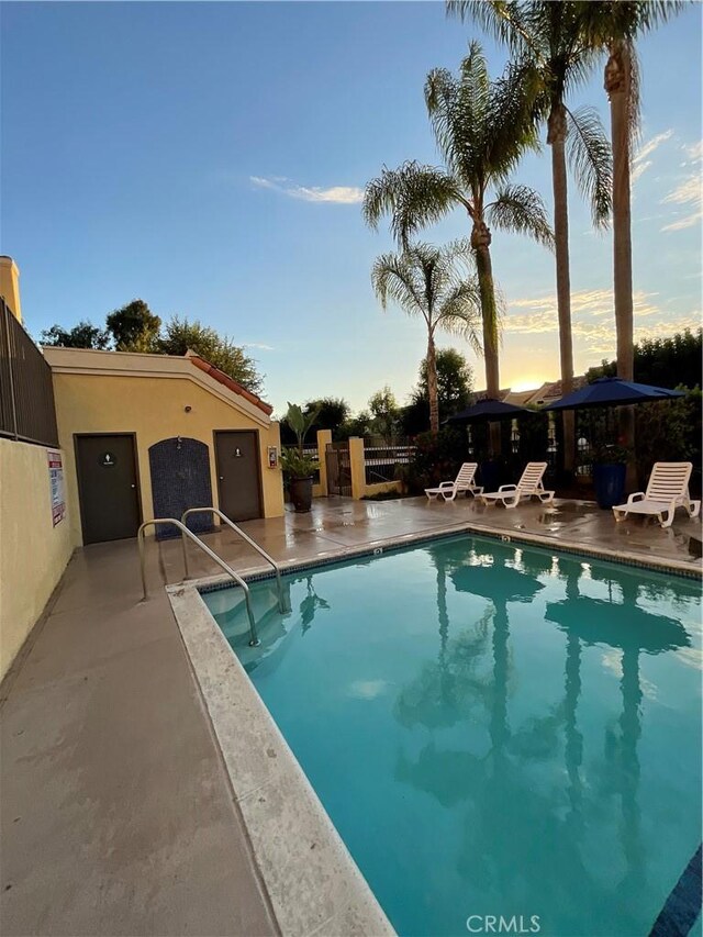 pool at dusk with a patio area