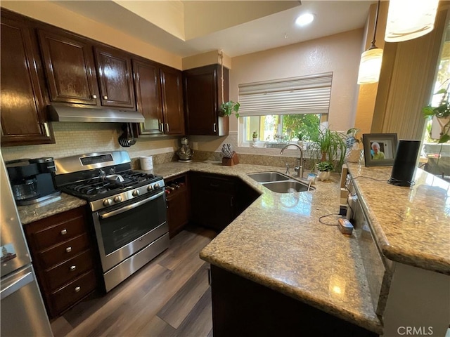 kitchen featuring dark hardwood / wood-style flooring, tasteful backsplash, gas range, sink, and decorative light fixtures