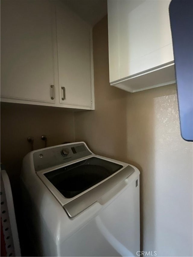 clothes washing area featuring cabinets and washer / dryer