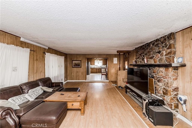 living room with a textured ceiling, light hardwood / wood-style floors, and wood walls