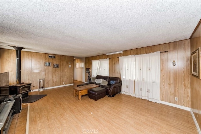 11507 Savage Ln, Apple Valley, CA 92308 - living room with wood finished floors, wooden walls, a textured ceiling, and a wood stove