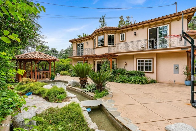 back of property featuring a gazebo, a patio area, and a balcony