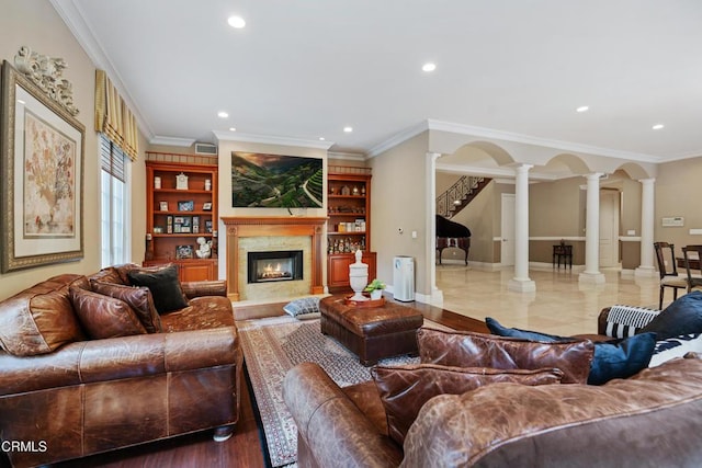 living room featuring built in features, crown molding, and decorative columns