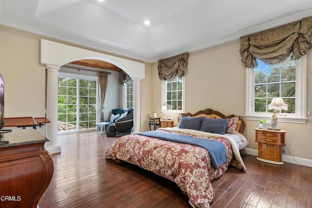 bedroom with wood-type flooring, ornate columns, a raised ceiling, and crown molding