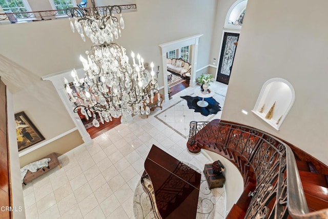 entryway with tile patterned flooring, a towering ceiling, and a chandelier