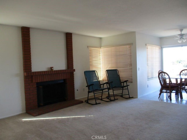 living area with ceiling fan, light colored carpet, and a brick fireplace