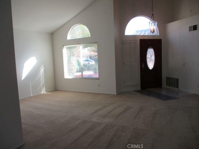 carpeted entrance foyer featuring high vaulted ceiling