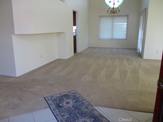 spare room featuring light colored carpet and a chandelier