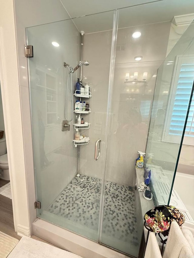 bathroom featuring wood-type flooring, toilet, and an enclosed shower