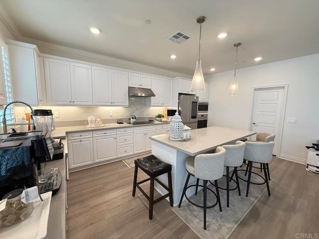 kitchen featuring a kitchen island, white cabinetry, pendant lighting, hardwood / wood-style flooring, and stainless steel refrigerator