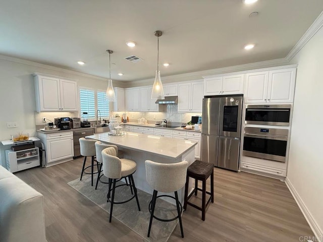 kitchen featuring dark wood-type flooring, appliances with stainless steel finishes, a breakfast bar, and white cabinets