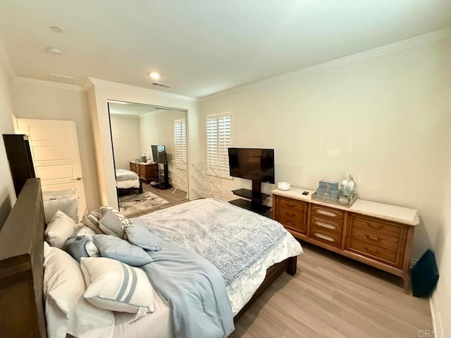 bedroom with a closet, ornamental molding, and light wood-type flooring