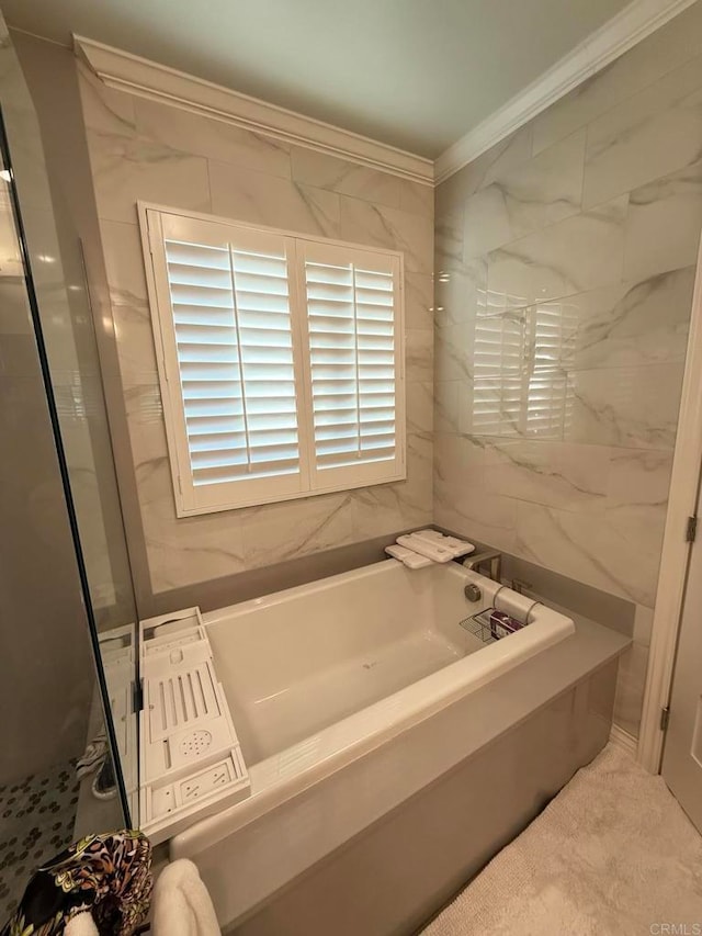 bathroom with ornamental molding and a bath