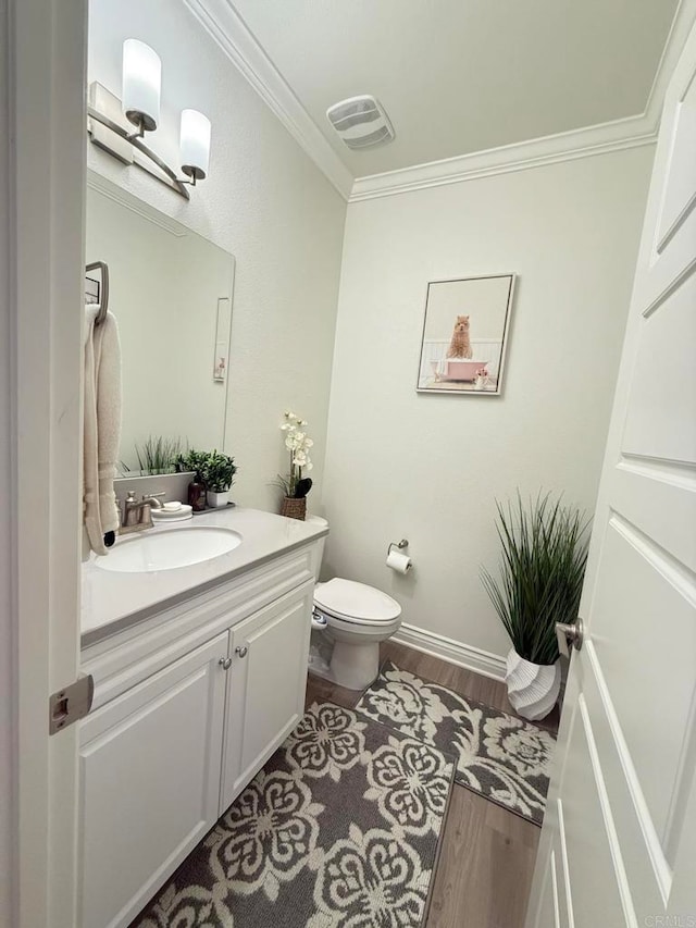 bathroom featuring vanity, toilet, ornamental molding, and hardwood / wood-style floors