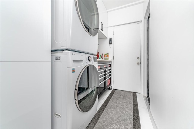 laundry room featuring dark tile patterned flooring and stacked washer / dryer