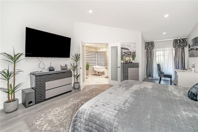 bedroom with light wood-type flooring and connected bathroom