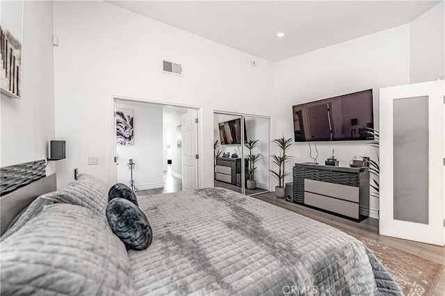 bedroom with a closet, wood-type flooring, and a high ceiling