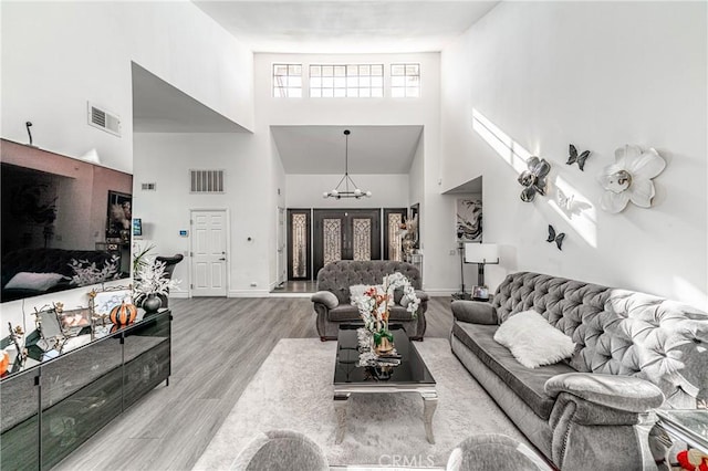 living room featuring a high ceiling, an inviting chandelier, and light hardwood / wood-style flooring