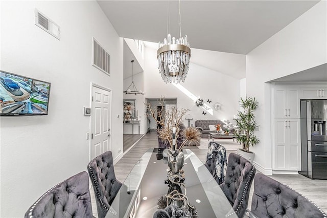 dining area featuring a chandelier, a high ceiling, and light hardwood / wood-style floors