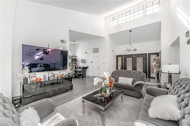 living room with a high ceiling, light hardwood / wood-style flooring, and a notable chandelier