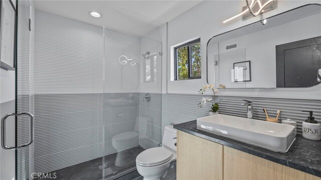 bathroom with vanity, an enclosed shower, tile walls, and toilet