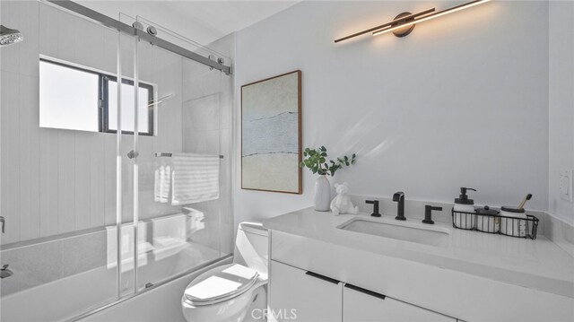 full bathroom featuring combined bath / shower with glass door, vanity, and toilet