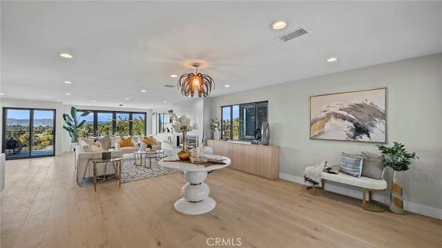 living room featuring plenty of natural light, light hardwood / wood-style floors, and a notable chandelier