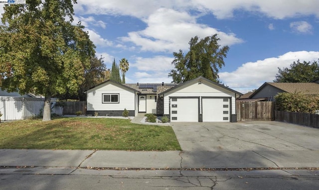 single story home with a garage, a front yard, and solar panels