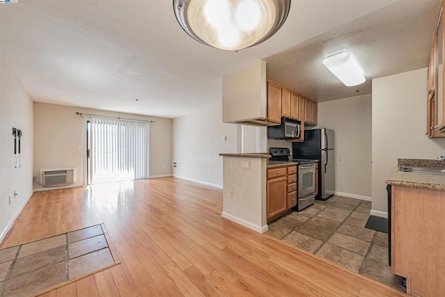 kitchen with a wall unit AC, light wood-type flooring, sink, and appliances with stainless steel finishes