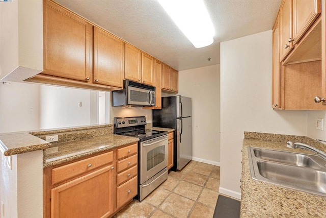 kitchen featuring light stone countertops, sink, kitchen peninsula, and stainless steel appliances