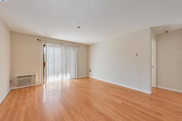 empty room with light wood-type flooring and a wall unit AC