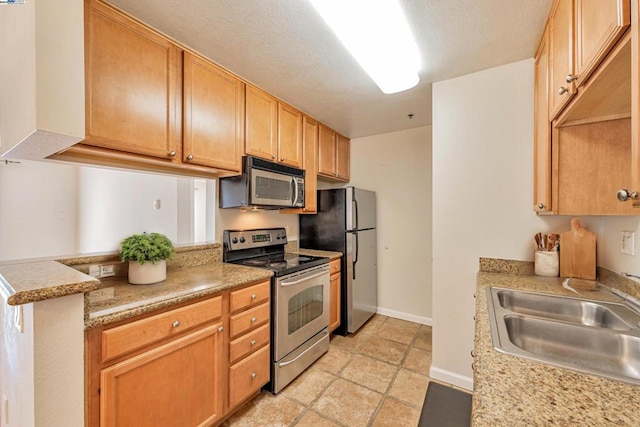 kitchen featuring a textured ceiling, kitchen peninsula, sink, and appliances with stainless steel finishes