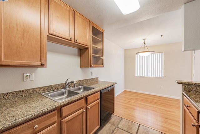 kitchen featuring pendant lighting, stone counters, sink, black dishwasher, and light hardwood / wood-style floors