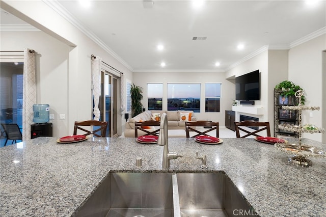 kitchen featuring light stone countertops, ornamental molding, and sink