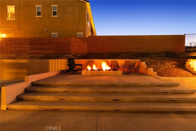 patio terrace at dusk featuring an outdoor fire pit