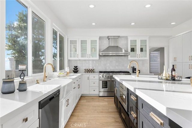 kitchen with white cabinetry, a wealth of natural light, wall chimney exhaust hood, and stainless steel appliances