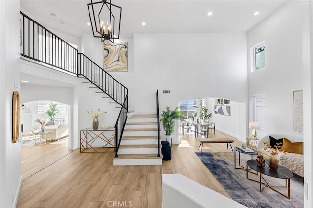 stairway featuring hardwood / wood-style floors, a high ceiling, and an inviting chandelier