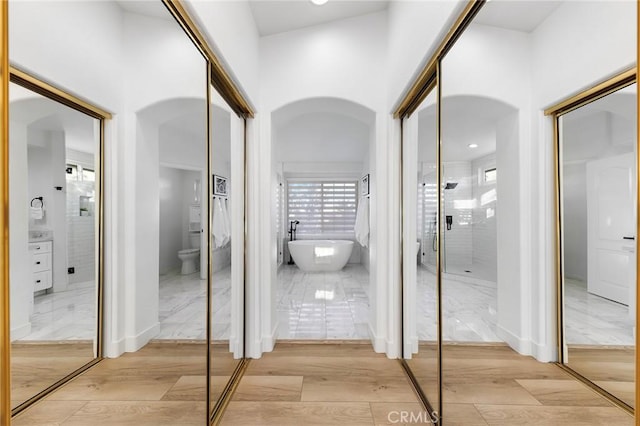 bathroom with hardwood / wood-style floors, vanity, a tub to relax in, and toilet