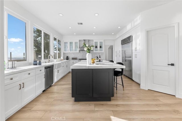 kitchen featuring light hardwood / wood-style flooring, white cabinets, stainless steel appliances, and a kitchen island