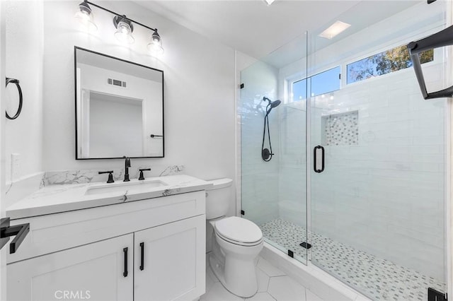 bathroom featuring tile patterned floors, toilet, vanity, and walk in shower