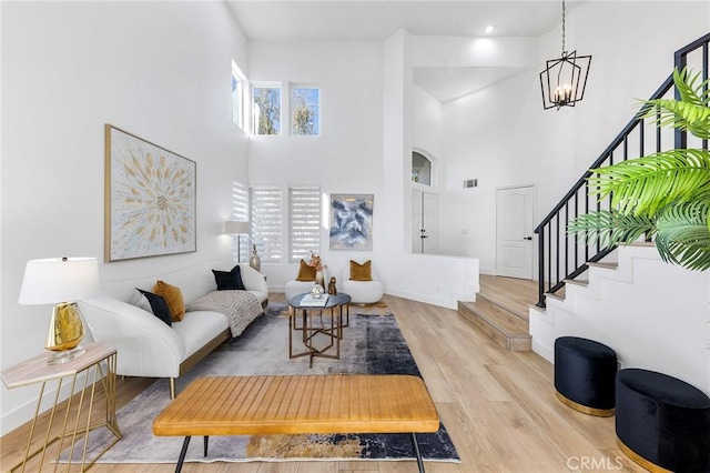 living room featuring plenty of natural light, light hardwood / wood-style floors, and a towering ceiling