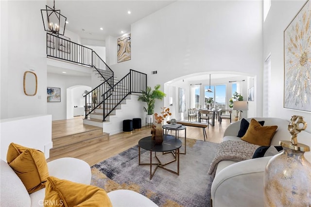 living room with a towering ceiling, light hardwood / wood-style floors, and a notable chandelier