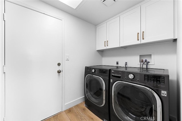 washroom featuring separate washer and dryer, cabinets, and light hardwood / wood-style floors