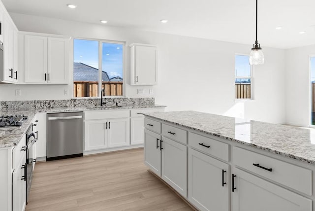 kitchen featuring sink, a wealth of natural light, hanging light fixtures, stainless steel appliances, and white cabinets