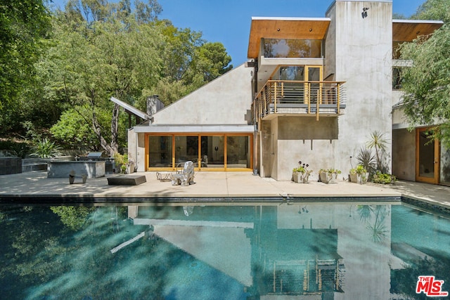 rear view of property featuring a patio and a balcony