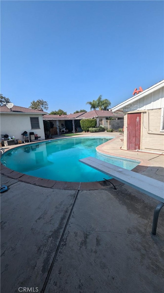 view of swimming pool with a diving board and a patio area